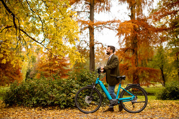 Fototapeta premium Young man with electric bicycle in the autumn park