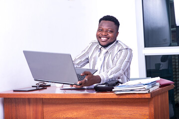 adult businessman holding laptop in office smiling.
