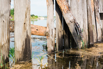 An old broken wooden fence is flooded by a flood on the river bank. Disaster