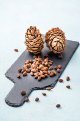 Unshelled pine nuts and cones on a slate board. Gifts of Siberia. Detox and cure for insomnia. Healthy vitamin nutrition. Vertical view