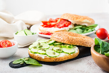 Obraz na płótnie Canvas Delicious bagel stuffed with feta, cucumber and pumpkin seeds and spinach leaves on a slate board. Light Vitamin Healthy Snack