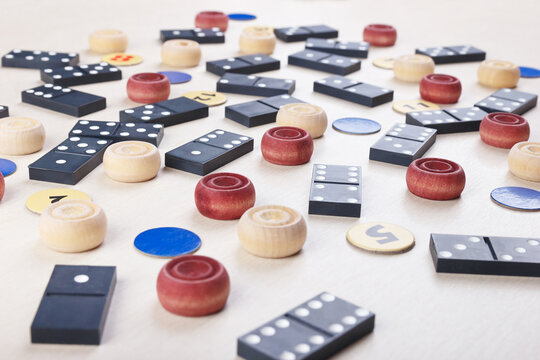Dominoes, chips and wooden checkers for board games on light table close up.