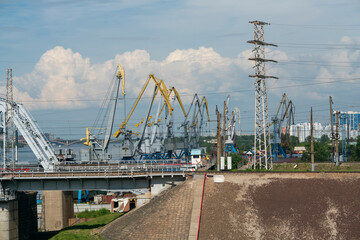 The loose abutment of the railway bridge against the background of harbor cranes.