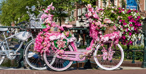 Fototapeta na wymiar Brücke in Amsterdam mit Fahrrädern, kunstvoll geschmückt mit Blumen bei den Grachten, Holland.
