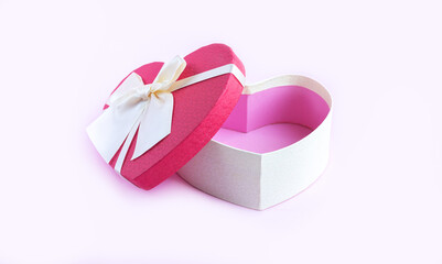 Open empty heart shape gift box with ribbon bow on pink table