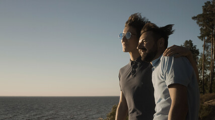 Fototapeta premium Happy gay couple hugging and admiring sea view, making future plans together