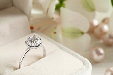 Beautiful engagement ring in box against blurred background, closeup. Space for text