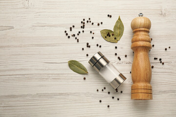 Salt and pepper shakers with bay leaves on white wooden table, flat lay. Space for text