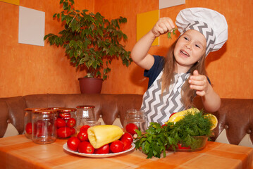 a little girl in the background of the kitchen of the house in an apron and a chef's cap shows vegetables cooking them for the winter, canning them for mother's day and Thanksgiving.