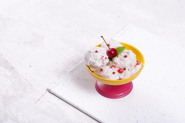 Obraz na płótnie Canvas Ice cream with red sweets and berries in a yellow and pink glass