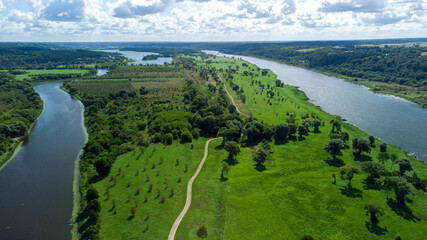 View of the rivers near the small forests under the blue sky with puffy clouds