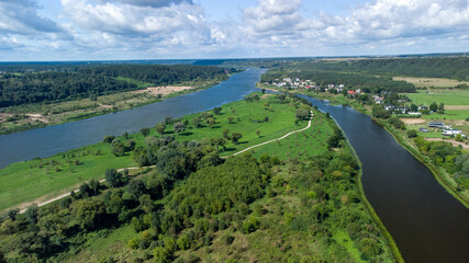 View of the rivers near the small forests under the blue sky with puffy clouds