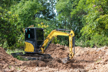 The excavator digs a soil. Digger loading trucks with soil. Excavator working on earthmoving at open pit mining. Excavator working on earthmoving at construction site.