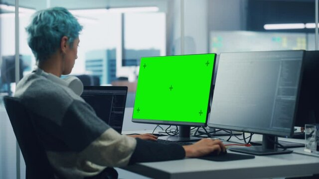 In Diverse Office: Female Programmer is Working on Green Screen Computer, Chroma key and Coding Language User Interface. Digital Entrepreneur Creating Software, e-Commerce App Design. Over Shoulder