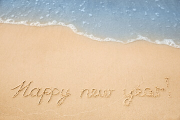 Fototapeta na wymiar Sandy beach with text Happy New Year washed by sea, above view