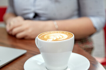 White mock up of cup of coffee on the table outside in foreground of women background. Copy space. Autumn coziness. Place for advertising