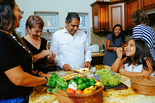 Happy multigenerational family preparing appetizer in kitchen while enjoying weekend together at home
