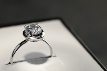 Beautiful engagement ring with gemstone in box on grey background, closeup