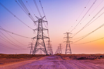 High voltage tower with electricity transmission power lines against the colorful sky, low angle...