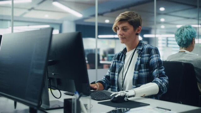 Diverse Body Positive Office: Portrait of Motivated Woman with Disability Using Prosthetic Arm to Work on Computer. Professional with Advanced Thought Controlled Body Powered Myoelectric Bionic Hand