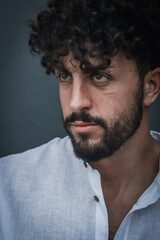portrait of a young man with beard and curly hair who looks angry and looks intently in front of him, close up	