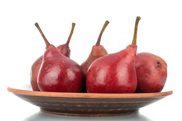 Several ripe red pears on a clay dish, close-up, isolated on white.