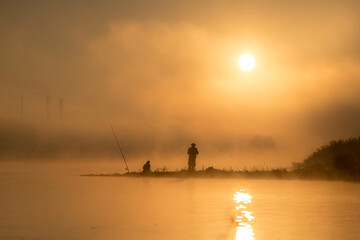 Wędkarze łowią ryby o wschodzie słońca nad rzeką © M