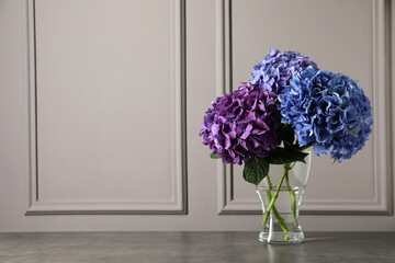 Bouquet with beautiful hortensia flowers on stone table near grey wall. Space for text