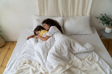 Calm mother and little boy sleep together cuddling. Kid came to mom bed at night scared with bad dream. Loving family of two enjoy early morning at home hugging in bedroom. Love and parenthood concept