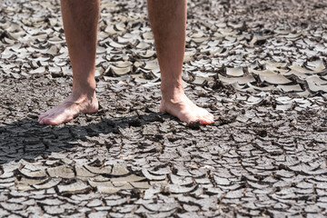 bare feet of a person on dry soil without plants close up
