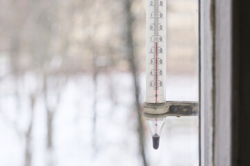 A thermometer outside a window showing minus ten 10 degrees in celsius, winter background