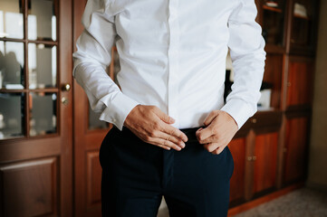Anonymous elegant male getting dress put on his belt.