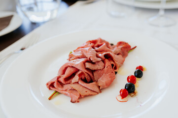 Sliced roast beef served in a a white plate. Restaurant food.