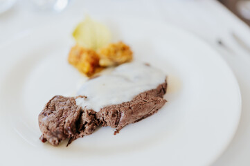 Close-up beef steak with sauce and potato on white background. Served in a porcelain dish in restaurant.