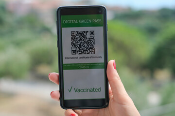 Woman hold covid19 vaccine qr code green pass certificate on a smartphone,tech