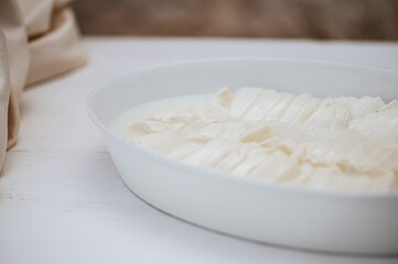 Close-up sliced mozzarella in a white porcelain plate.