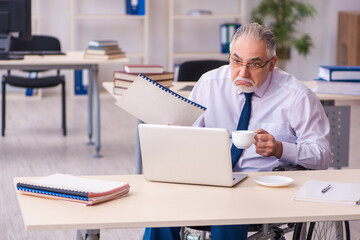 Old male employee in wheel-chair drinking coffee during break