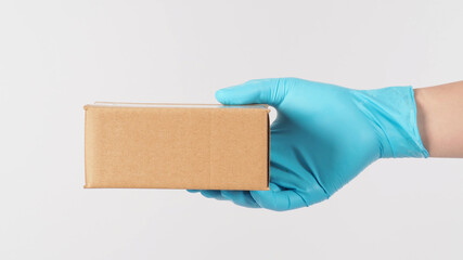 One right Hand wearing blue medical glove and holding brown box on white background.