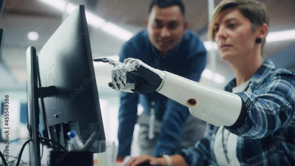 Poster Teamwork In Diverse Office: Smiling Project Manager Talks with Happy Woman with Disability with Prosthetic Arm to Work on Desktop Computer. Professionals Create e-Commerce Software App Solution