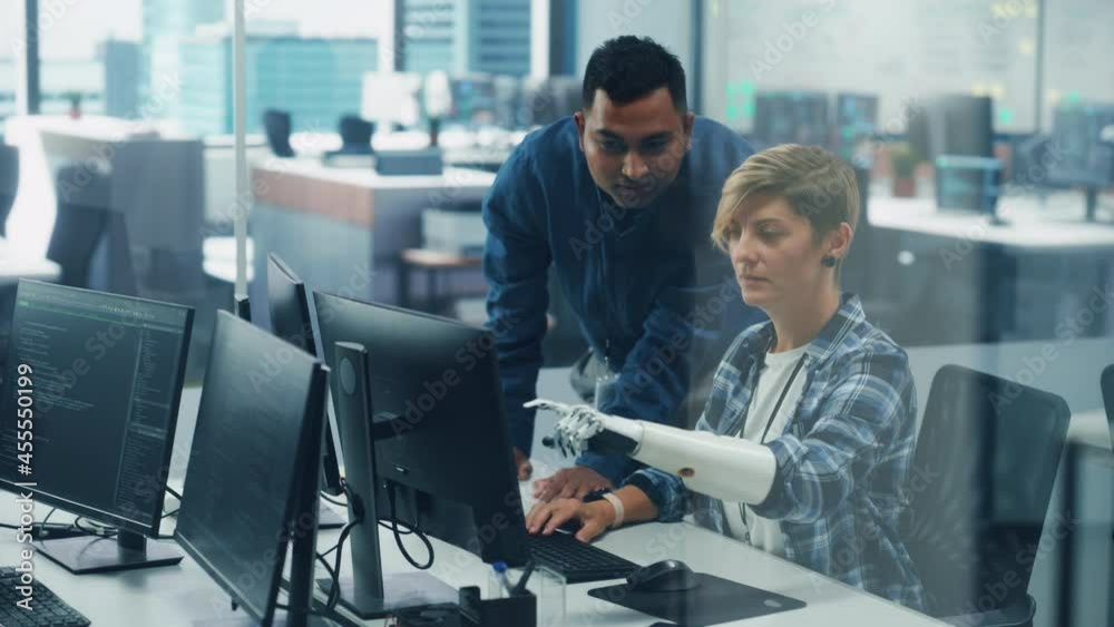 Poster Teamwork In Diverse Inclusive Office: Project Manager Talks with Woman with Disability with Prosthetic Arm Work on Desktop Computer. Professionals Software Engineers Create e-Commerce App Solution