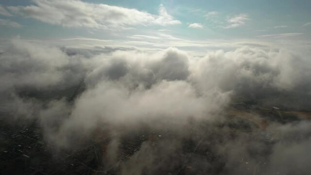 Moving white clouds blue sky on coastline sea surface scenic aerial view summer. Drone flies turn high in blue sky through fluffy clouds on panorama of city. Sun is hidden. Fog. Dramatic scene