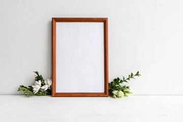 Fashionable female background on a white table - flowers and an empty photo frame. Wedding female background. Blank for a postcard.