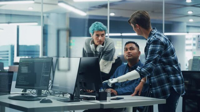 Team Meeting In Diverse Office: Project Manager with Disability points Prosthetic Arm at Computer Screen Talks with Multi-Ethnic Specialists. Software Engineers Collaborate on Creative Solution