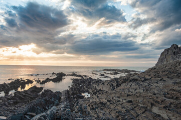 Dramatic scene with big rocks, sea, sunbeam and sundown