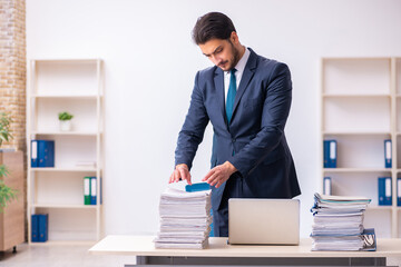 Young businessman employee and too much work in the office