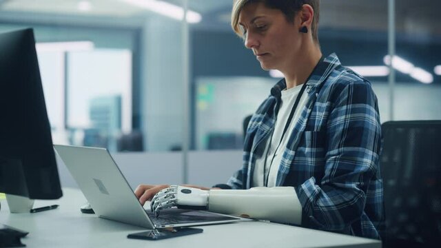Diverse Body Positive Office: Portrait of Motivated Woman with Disability Using Prosthetic Arm to Work on Computer. Professional with Futuristic Thought Powered Myoelectric Bionic Hand