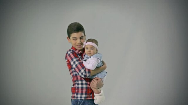 Good looking and loving Brother holding little baby Sister hugging , kissing . Adorable . Happy lifestyle kids .