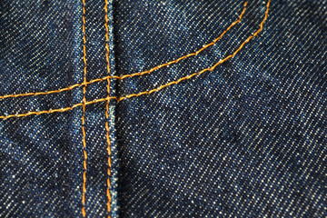 yellow sewing on blue jeans from close up