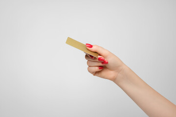 Plastic gold credit card in a woman's hand, red nail polish