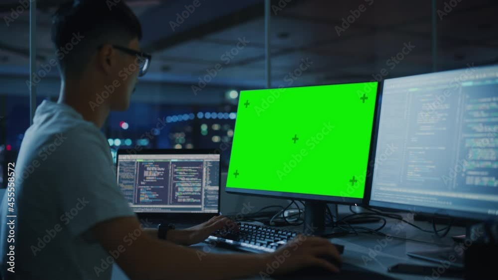 Poster Night Office: Young Japanese Man in Working on Green Screen Chroma Key Desktop Computer. Team of Programmers Typing Code, Creating Modern Software, e-Commerce App Design, e-Business Programming